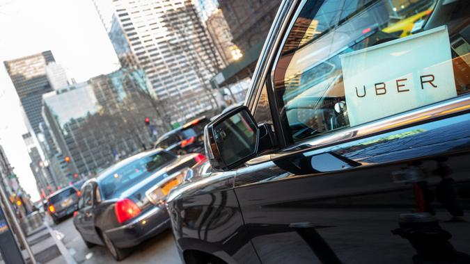 New York City, USA - March 5, 2016: Uber car service with sign in car window is waiting to pickup passengers on 6th Avenue in Manhattan, NY.