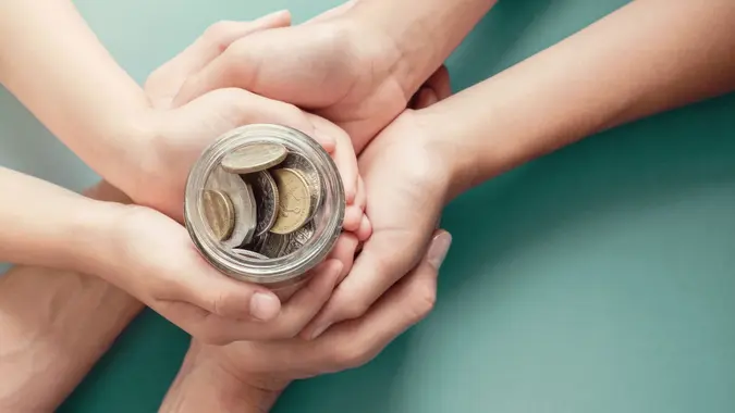 child and parent hands holding money jar, donation, saving, charity, family finance plan concept, Coronavirus economic stimulus rescue package, superannuation concept.