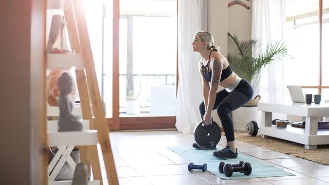 A Young athletic woman doing weight training at home during lockdown.