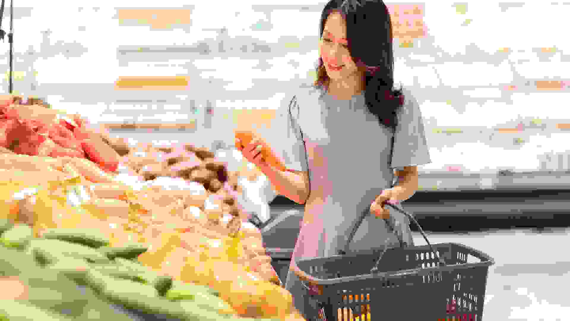 The young girl is choosing to buy vegetables at the supermarket.