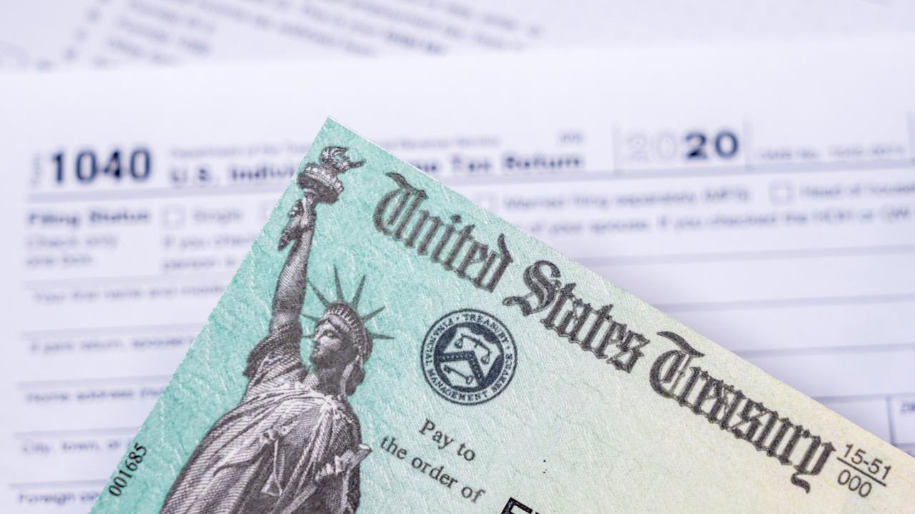 US Treasury stimulus check laying on a form 1040 tax return for 2020 to illustrate questions about qualification for payment.
