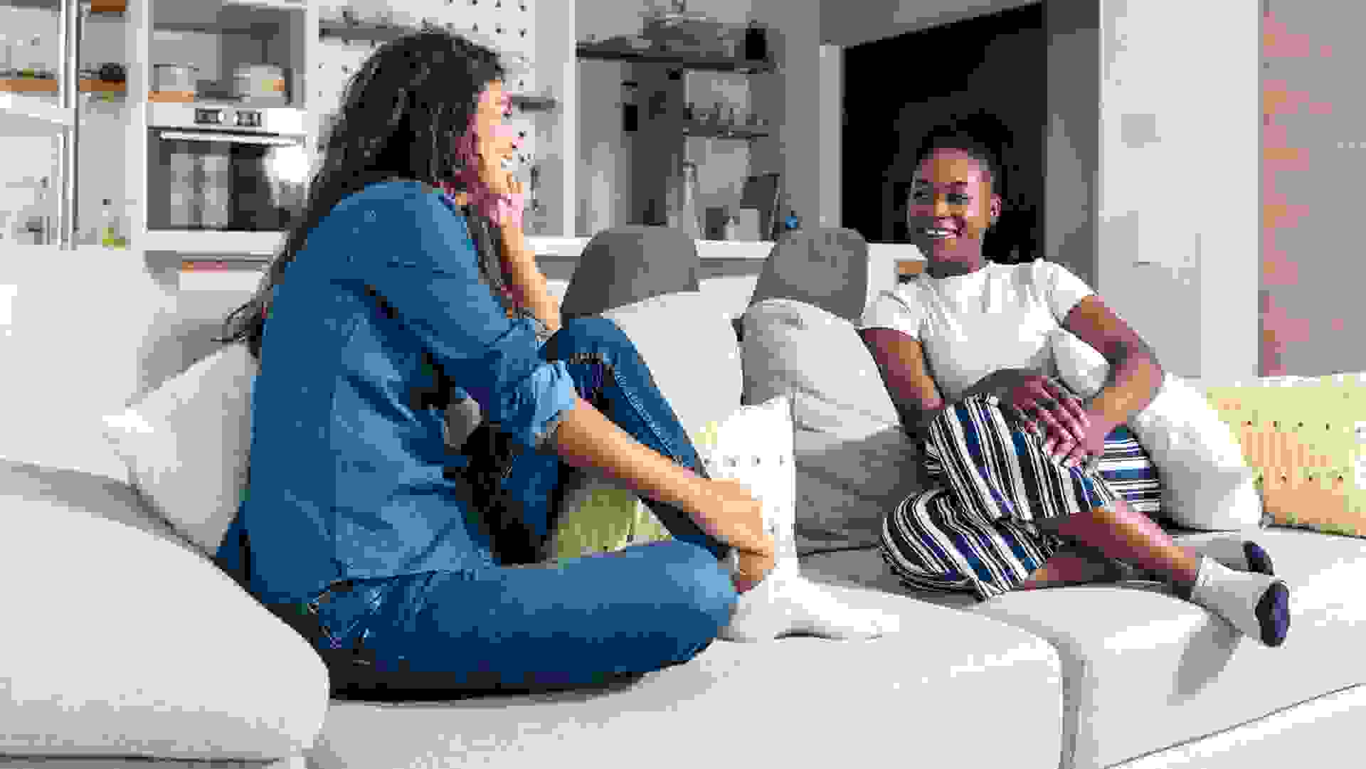 Young homeowner woman sitting on a sofa with a young female student who wants to rent an apartment to live in while she is studying in college and discussing price terms and obligations.
