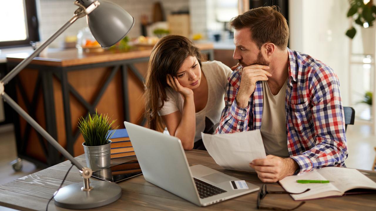 Frustrated couple checking bills at home using laptop.