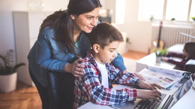 Mother helps son how to use a lap top and internet.