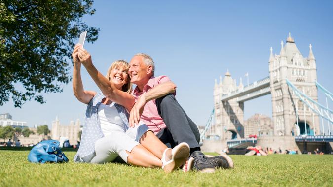 Happy couple of tourists in London taking a selfie with Tower Bridge at the background.