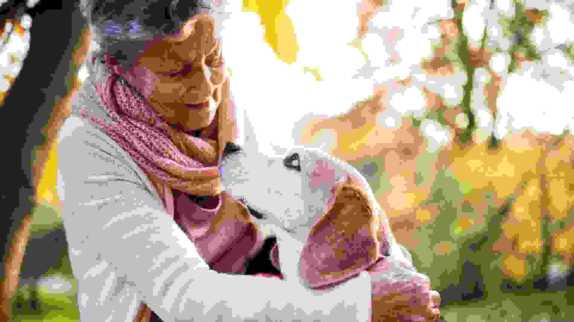 An elderly woman with dog in autumn nature.