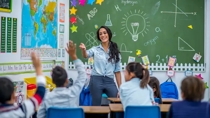 An Ethnic teacher is leading a class of elementary school children.