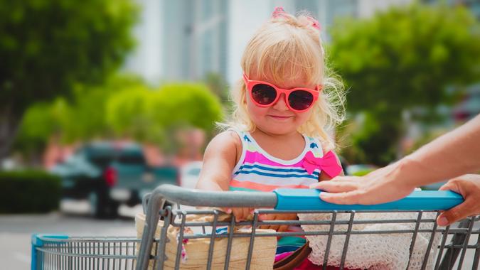 Shopping with kids- cute little girl in shopping cart in the city stock photo