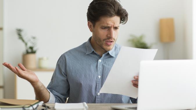 Confused Guy Reading Mail Letter Or Debt Notification Indoors stock photo