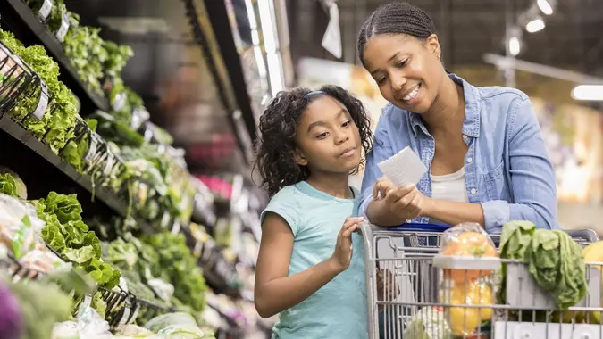 Mother and daughter grocery shop together using list stock photo