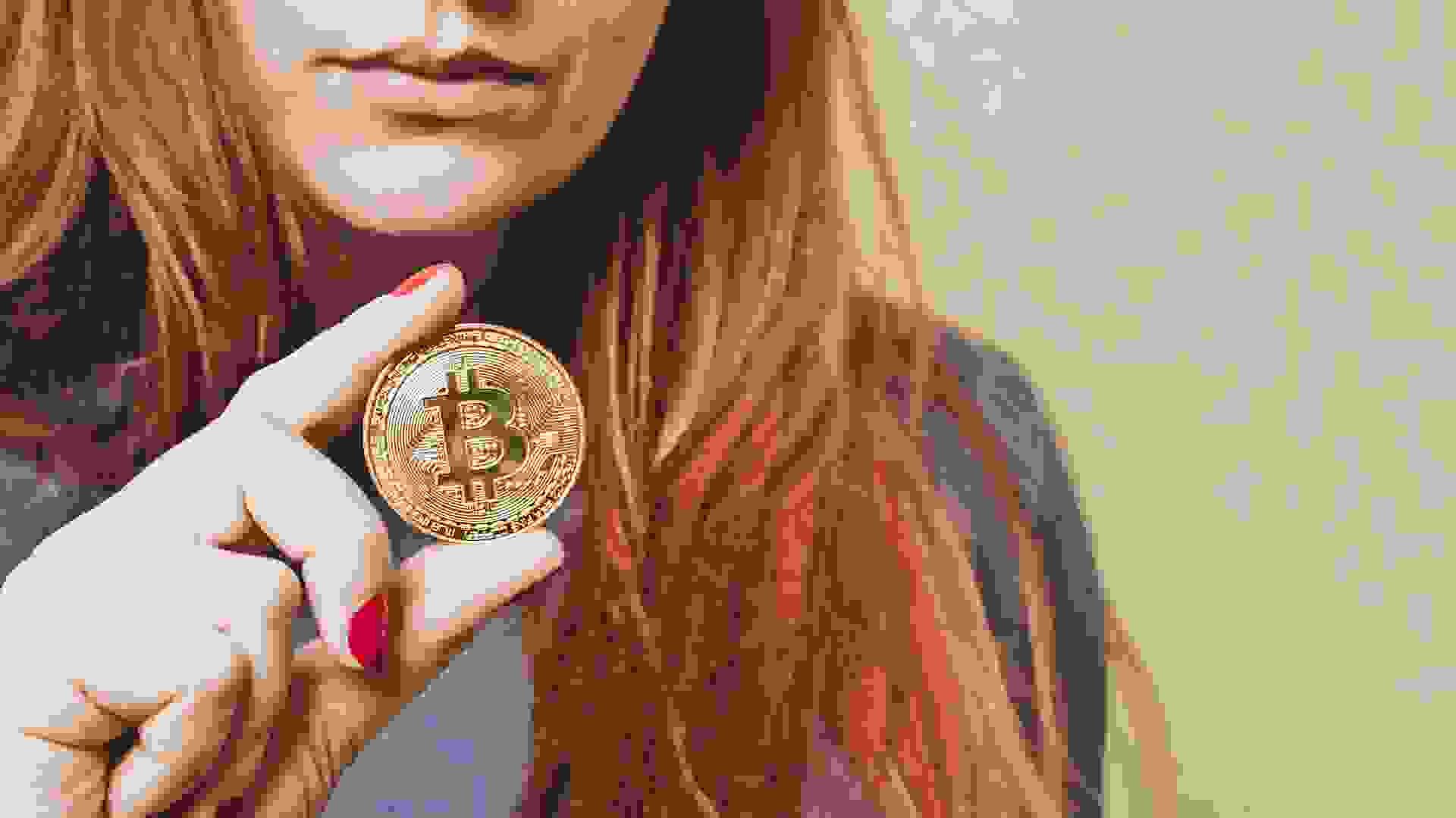 Red-haired woman holds bitcoin gold coin in her hand stock photo