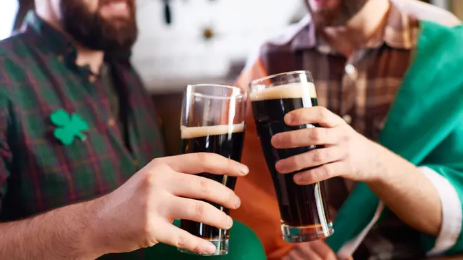 Close-up of cheerful men in costume clinking beer glasses while celebrating St Patrick day.