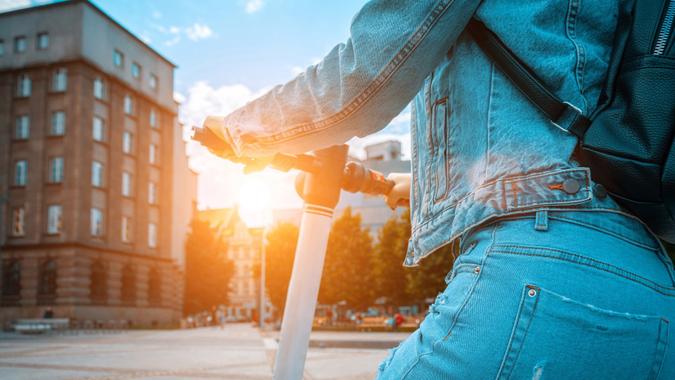 Scooter nature. Kick electric city bike using from business woman. Electric scooters for public share standing outside. stock photo