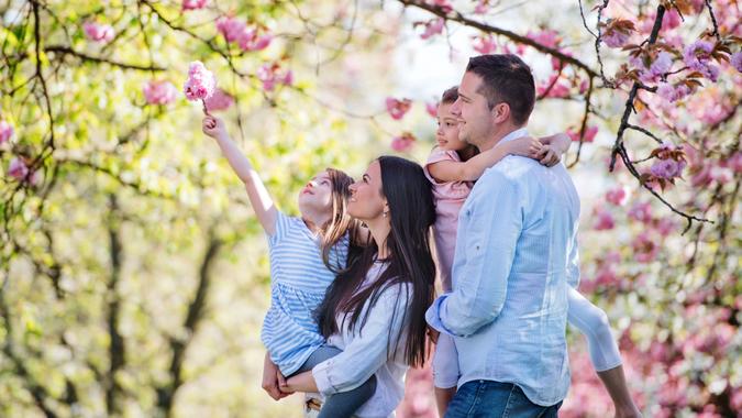 Side view of young parents with small daugthers standing outside in spring nature.