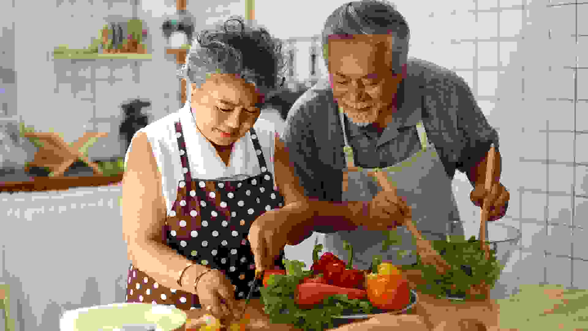 Happiness senior elderly couple having fun in kitchen with healthy food for working from home.