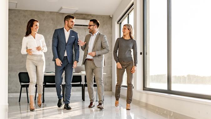 Group of happy entrepreneurs communicating while walking in the office.