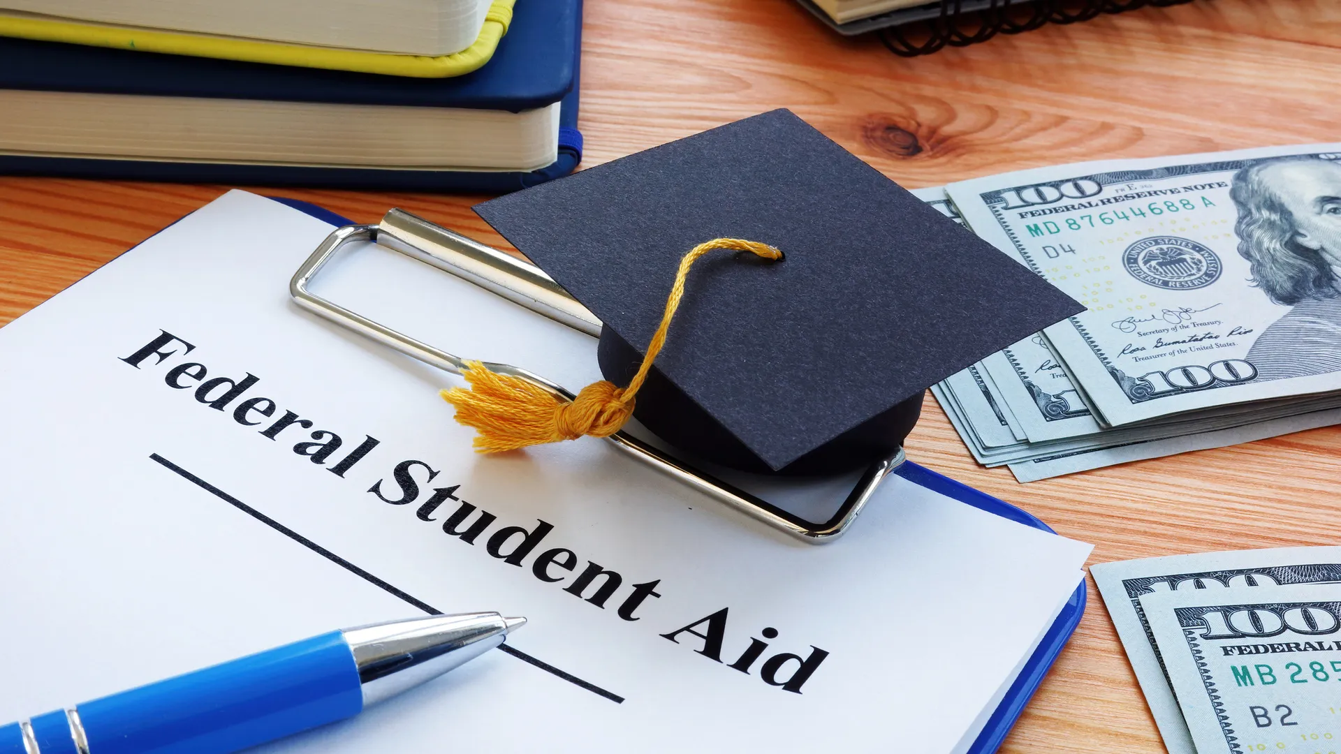 Federal student aid papers and small Square academic cap.