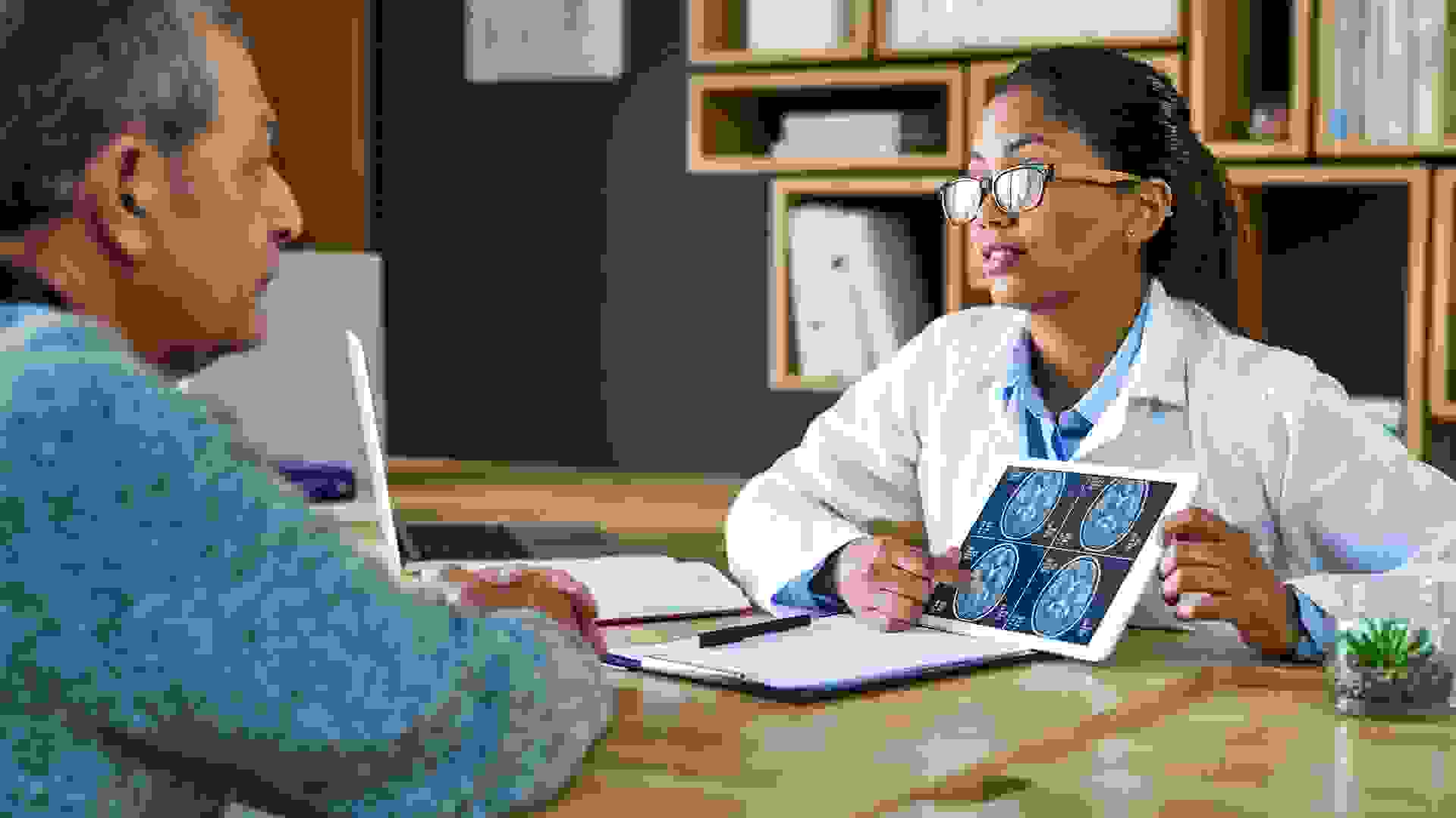 Shot of a doctor using a digital tablet to discuss a brain scan with a senior patient.