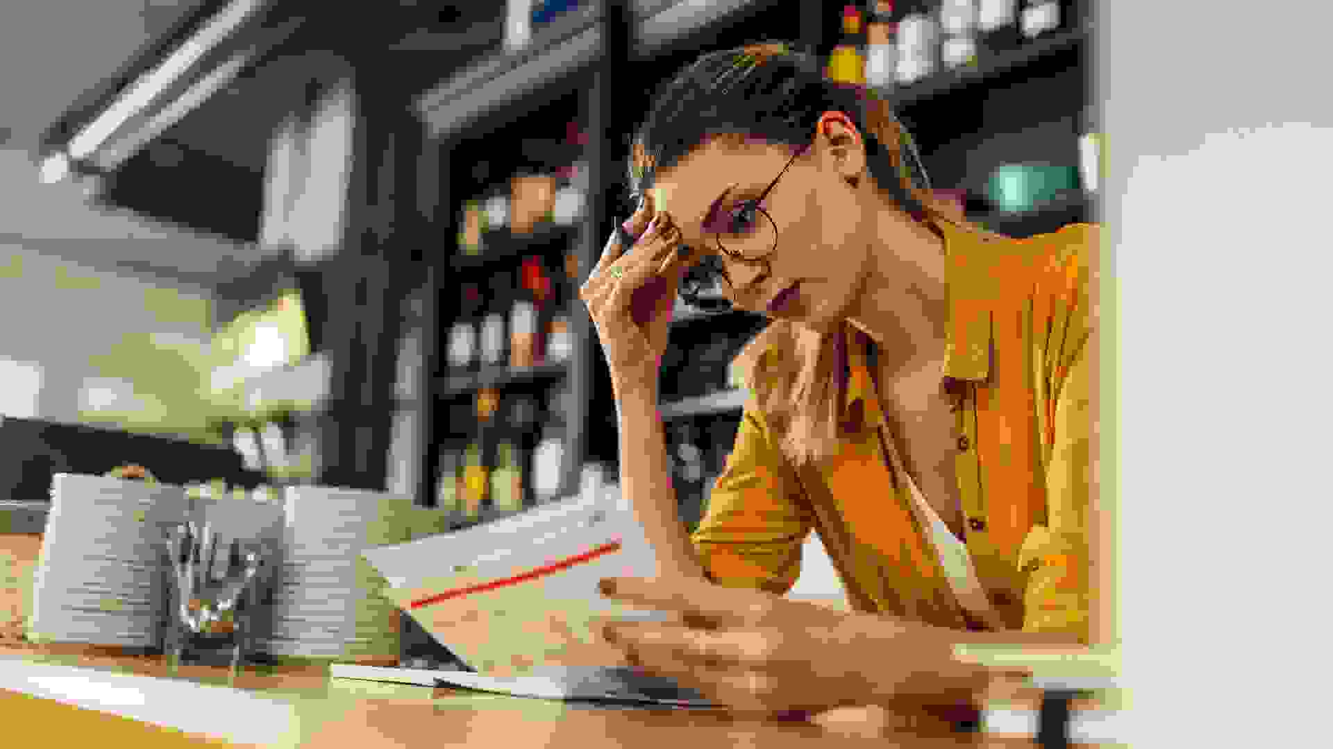 Owner of a restaurant checking financial business documentations while standing behind counter.