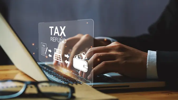 Businessman hand using a laptop with bar  TAX REFUND and refund tax of duty taxation business, tax form, and wallet money being demonstrated on the screen media, online for tax payment.