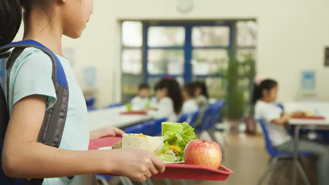 Girl holding food tray in school cafeteria stock photo