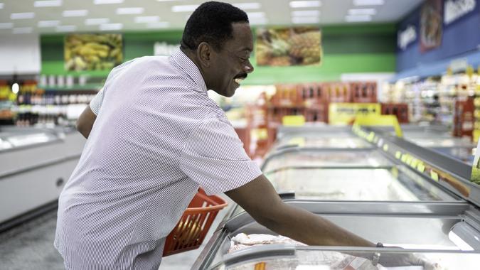 Mature man looking and choosing product in the supermarket freezer stock photo