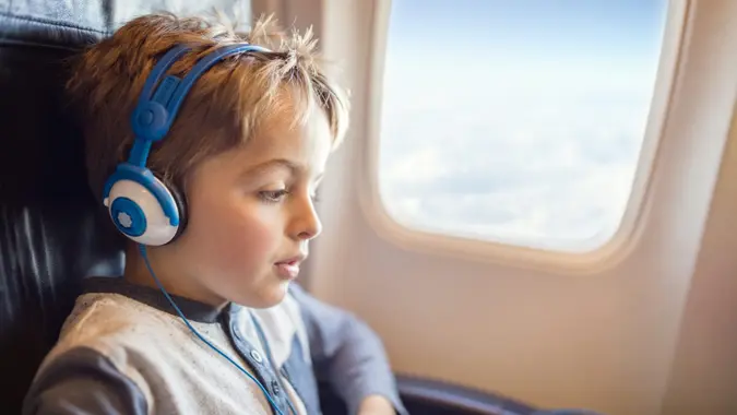 Boy with headphones watching and listening to in flight entertainment on board airplane.