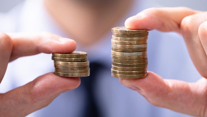 Man Comparing Two Coin Stacks stock photo