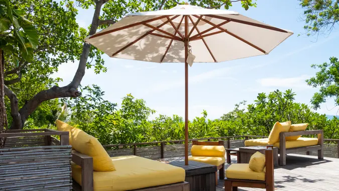 Wooden, yellow sofa couch with umbrella at the outdoor patio.