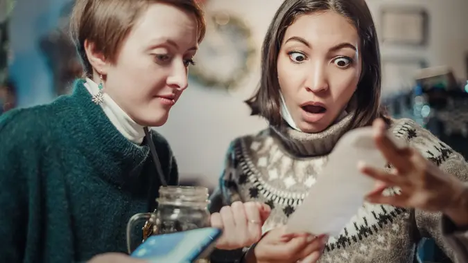 Asian woman stares at the check for dinner at the restaurant, her eyes bulging. The concept of inflation and devaluation of money and reduction of purchasing power of the population. stock photo