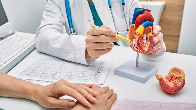 Cardiology consultation, treatment of heart disease. Doctor cardiologist while consultation showing anatomical model of human heart stock photo