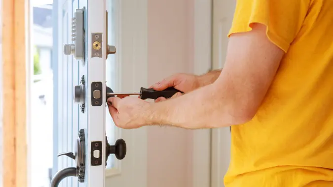 Worker installing or repairing new lock handyman repair the door lock.