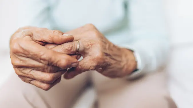 Heartbroken elderly woman holding he husbands wedding ring.
