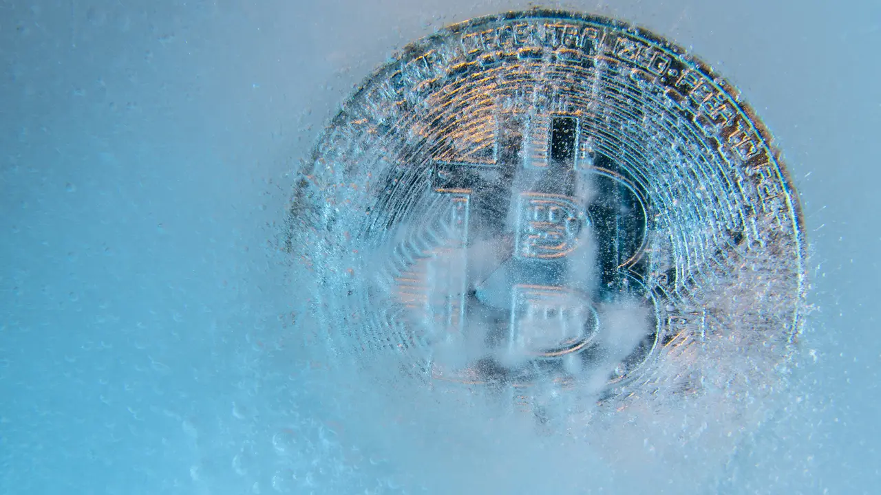 Prague, Czech Republic - October, 2019: Silver Bitcoin, bit coin online digital currency frozen in the blue ice.