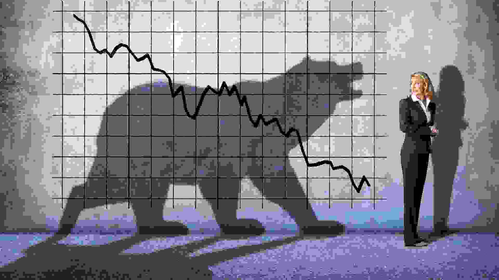 A businesswoman looks over her shoulder with concern at  a descending stock chart and an ominous shadow of a bear that is cast on the wall above her.