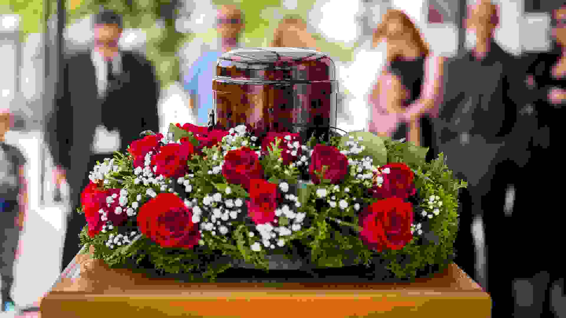 Funerary urn with ashes of dead and flowers at funeral.