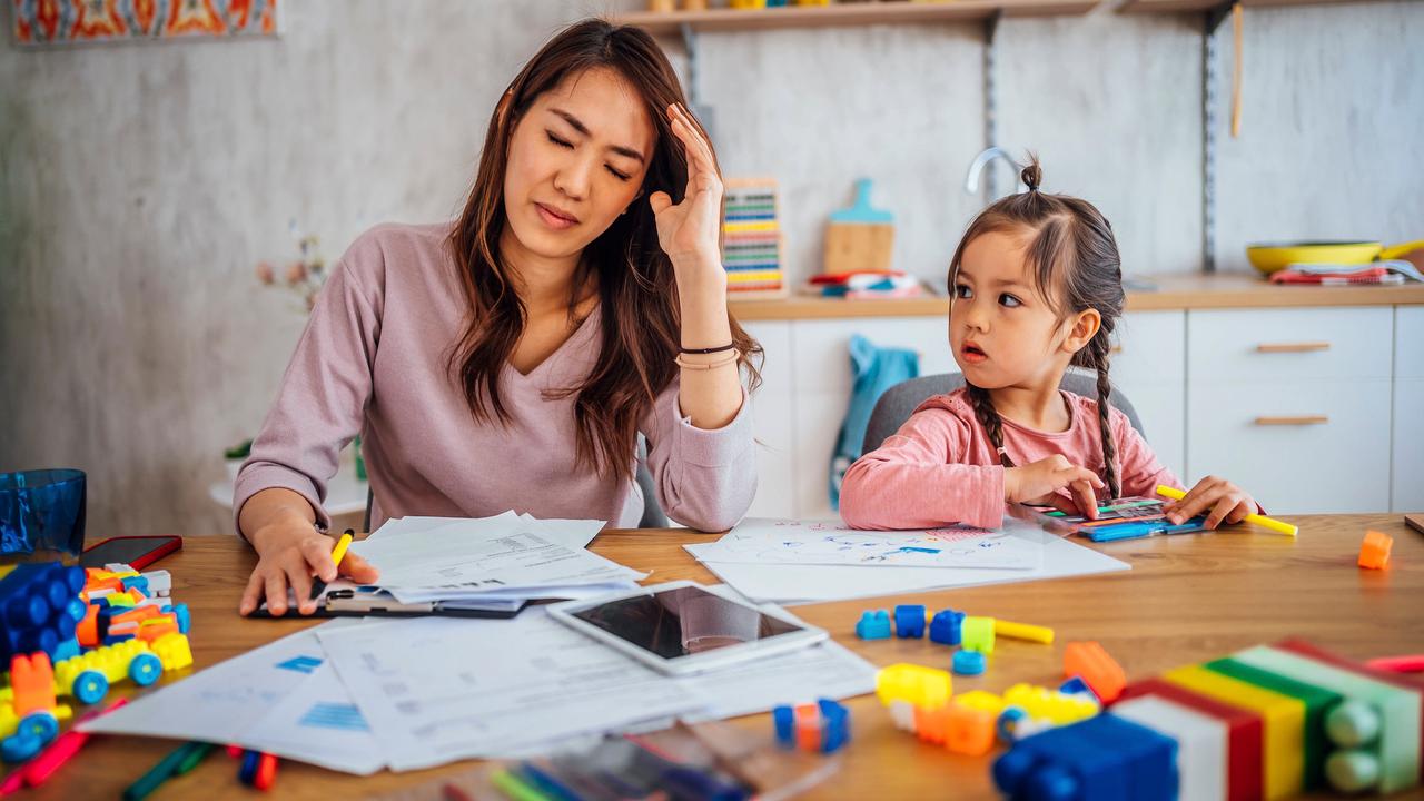Young worried mother going through her financials, daughter sit nearby and play.