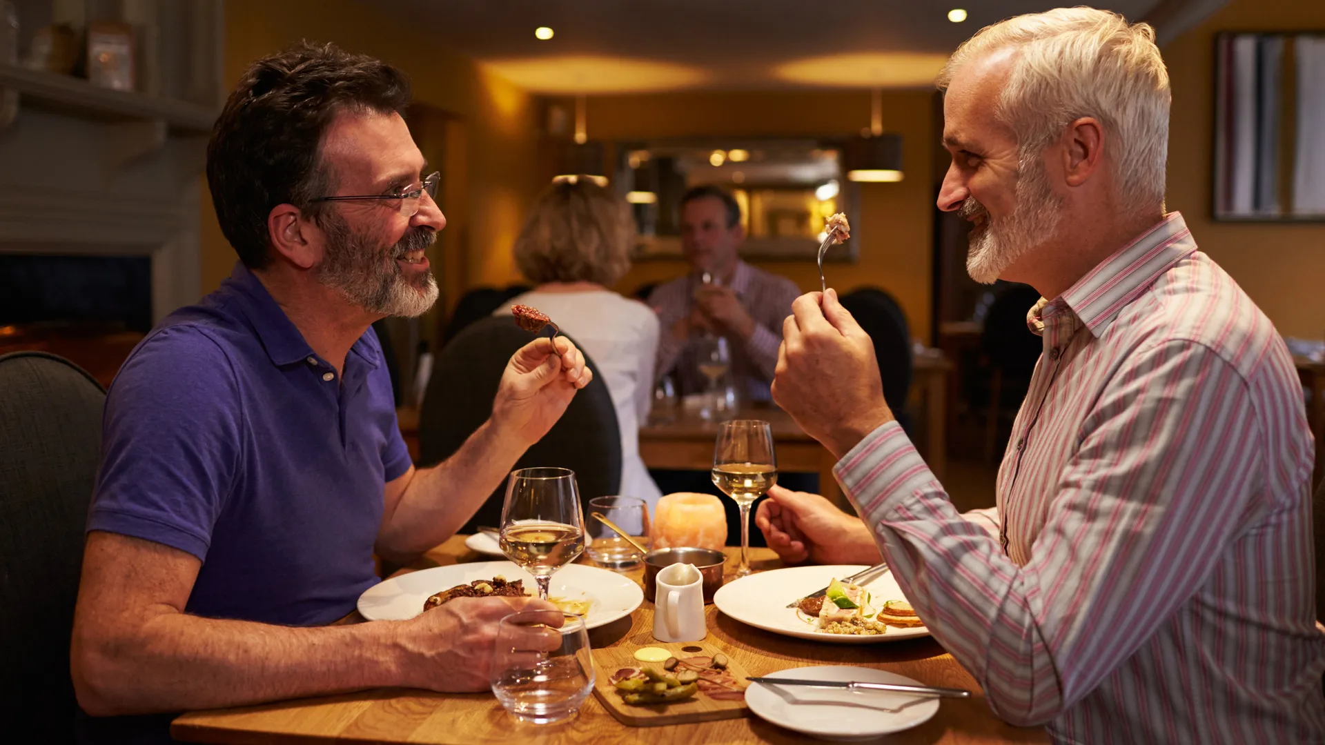 Middle aged male couple eating evening meal in a restaurant.