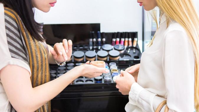 Young pretty woman chosing color cosmetic and beauty consultant in shop or beauty salon.