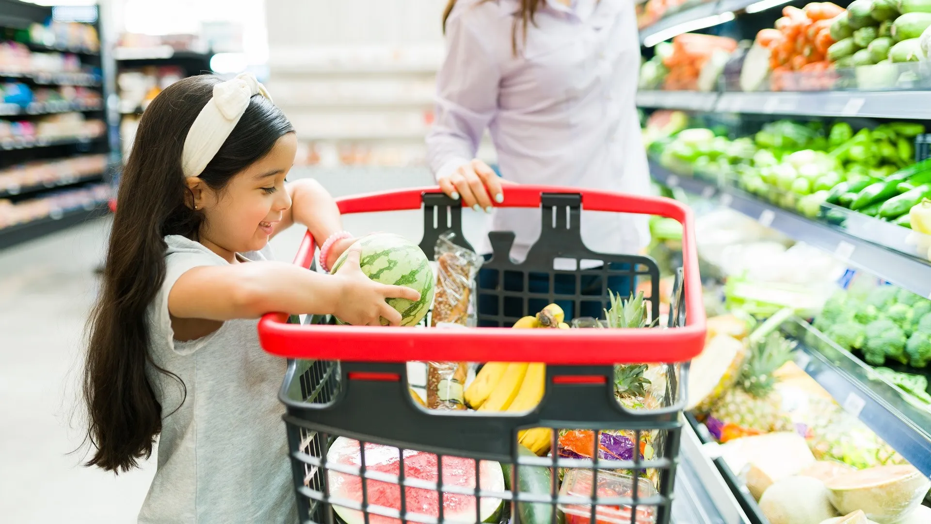 Cute kid helping mom shopping groceries stock photo