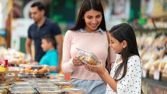 Beautiful mother and daughter looking at a box of cookies in bakery section of supermarket stock photo