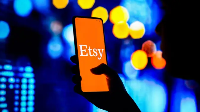 Mandatory Credit: Photo by Rafael Henrique/SOPA Images/Shutterstock (12907906l)In this photo illustration, a silhouetted woman holds a smartphone with the Etsy logo displayed on the screen.
