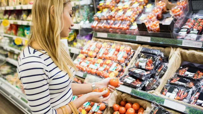 Thoughtful woman taking products on shelf stock photo