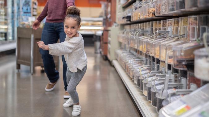 Girl dragging her dad to the candy section at the grocery store... stock photo
