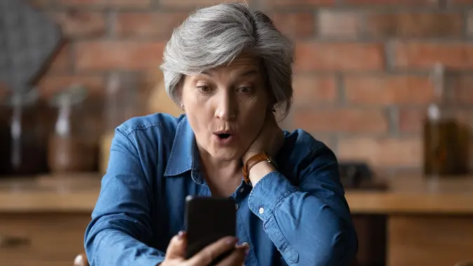 Close up overjoyed mature woman looking at phone screen stock photo
