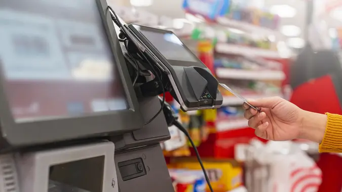 Close up unrecognize person human female hand with pos cashier machine Retail, credit card payment service. Customer paying for order of cheese in grocery supermarket store shop. stock photo