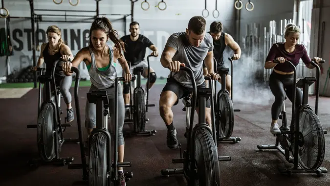 Large group of athletic people having sports training on exercise bikes in a gym.