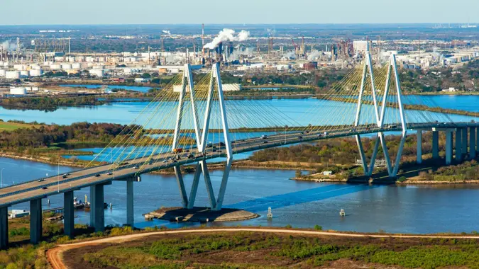 The Fred Hartman Bridge spanning the San Jacinto Bay in Baytown, Texas located in Harris County just outside of Houston with a large oil refinery in the background.