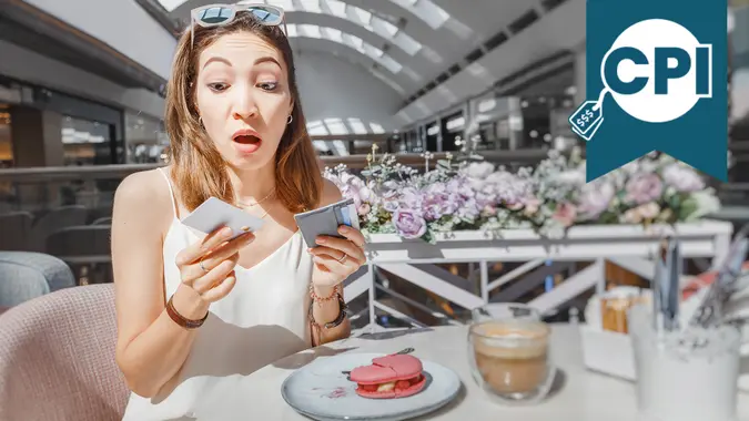 Puzzled girl thinking how to pay for breakfast in a cafe - by a credit card or cash.