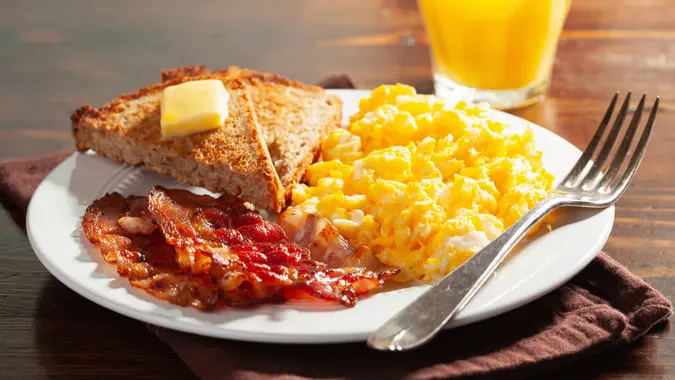 traditional scrambled egg breakfast with bacon and toast.